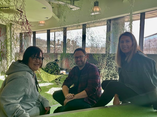 Three people sitting together under hanging plants at Electric Works
